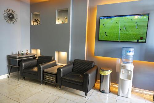 a waiting room with two chairs and a tv on the wall at RİO's HOTEL KURTKÖY in Istanbul