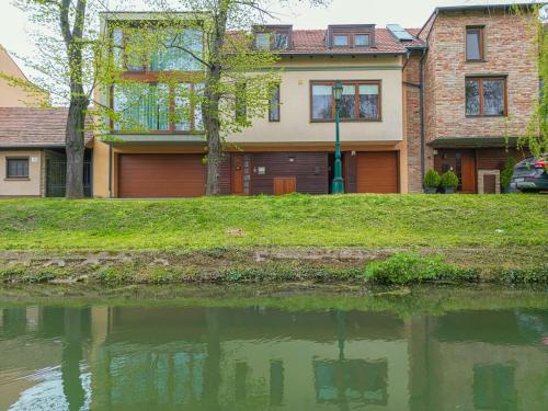 a house sitting next to a body of water at Komló Apartman - Gyula in Gyula