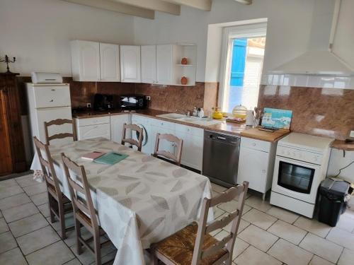a kitchen with a table and chairs and a kitchen with white cabinets at Les Hortensias in La Poultière