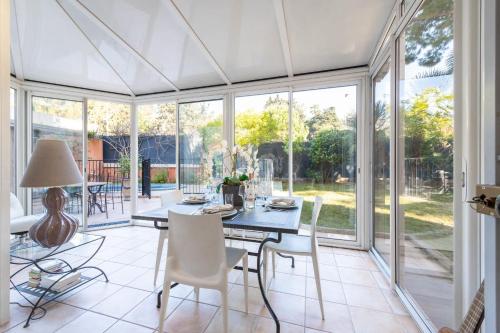 une véranda avec une table, des chaises et des fenêtres dans l'établissement 3-Br Apartment with Private Pool & Sea View, à Cannes