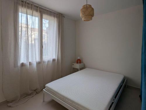 une chambre blanche avec un lit et une fenêtre dans l'établissement Appartement Saint Ruf, à Avignon