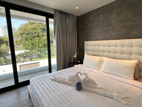 a bedroom with a white bed with a large window at Pattaya Near Beach & Walk Street Luxury Villa in Pattaya South