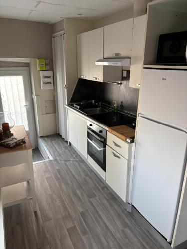 une cuisine avec des armoires blanches et un réfrigérateur blanc dans l'établissement la saline, à Peyriac-de-Mer