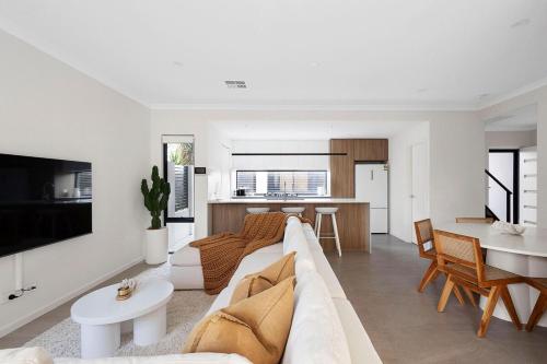 a white living room with a couch and a table at Urban Haus - Hillarys in Perth
