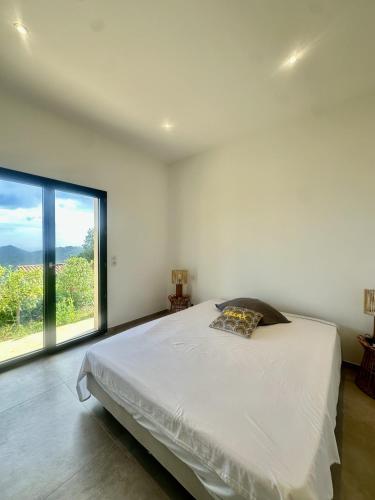 une chambre blanche avec un lit et une grande fenêtre dans l'établissement Superbe villa vue mer et piscine, à Monticello
