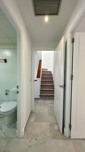 a bathroom with a toilet and a staircase at Casa doble Almadraba in Novo Sancti Petri
