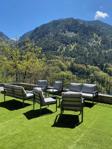 a group of chairs sitting on the grass with a mountain at Quiet House Sa Calma in Andorra la Vella