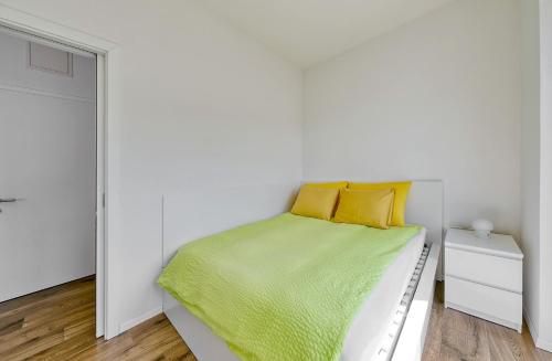 a white bedroom with a bed with yellow pillows at Apartments Trnovo in Ljubljana