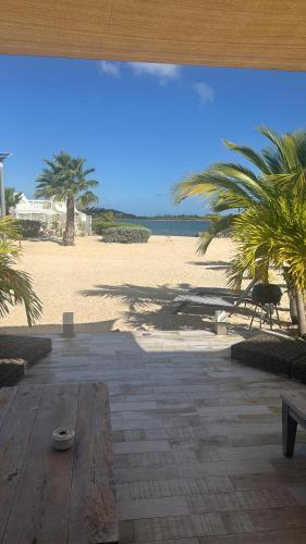 a patio with a view of a beach with palm trees at Coco Beach in Baie Nettle