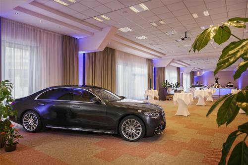 a black car parked in a room with tables at NH Vienna Airport Conference Center in Schwechat