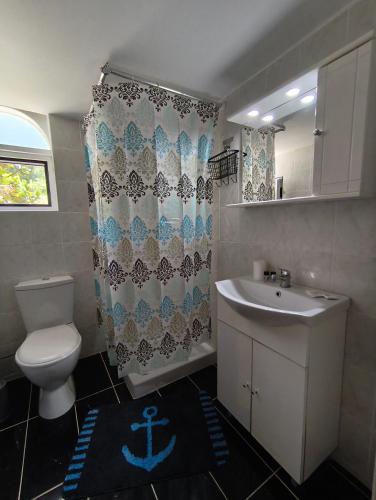 a bathroom with a sink and a toilet and a shower curtain at Cozy apartment in Ialysos