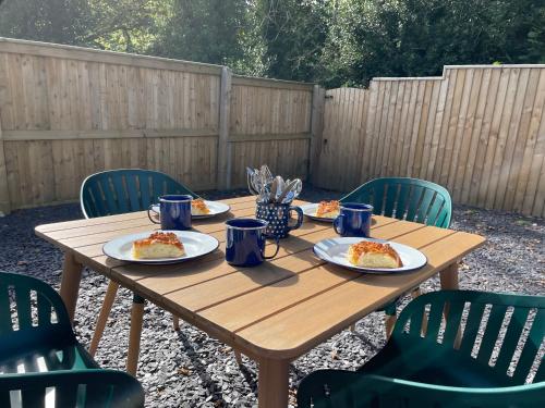 a wooden table with plates of food on it at Your Saundersfoot getaway - relax explore and make memories at Berts Bungalow in Saundersfoot