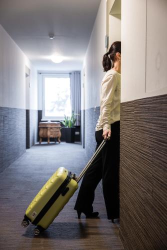 a woman pulling a yellow suitcase in a hallway at Hotel Bannewitz B&B in Bannewitz