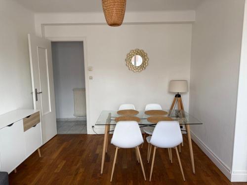 une salle à manger avec une table en verre et des chaises blanches dans l'établissement Comfort in the Heart of Dijon, à Dijon