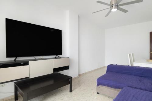 a living room with a tv and a blue couch at Casa En El Centro De Barbate in Barbate