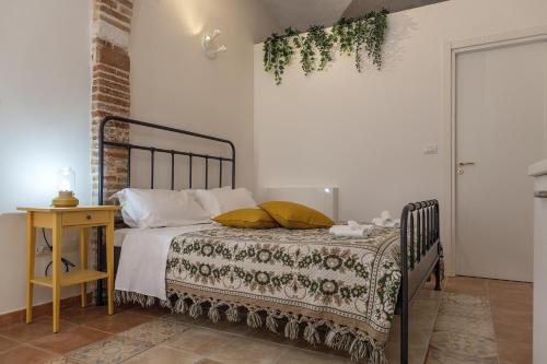 a bedroom with a bed and a table with a plant on the wall at Il sito del cantastorie-Affitti Brevi Italia in LʼAquila