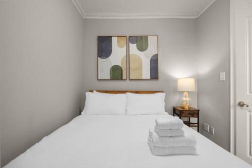 a white bedroom with a bed with towels on it at Stylish NYC Retreat Near Top Attractions in New York