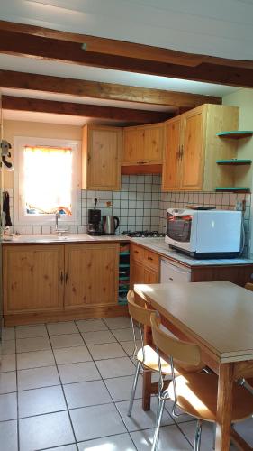 - une cuisine avec des placards en bois, une table et un évier dans l'établissement a 10 mn d Angers maisonnette independante, à Brain-sur-lʼAuthion
