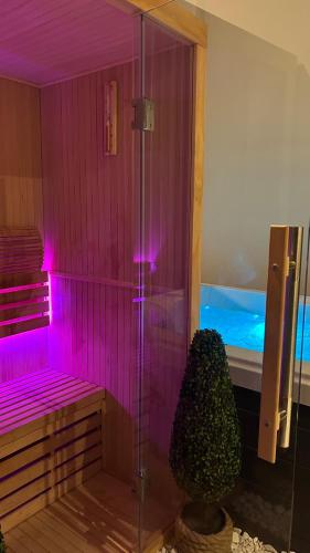 La salle de bains est pourvue d'une douche avec des lumières violettes et une plante. dans l'établissement Duplex Luxe - Sauna & Jacuzzi Privatif, à Montrouge