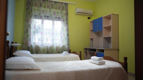 a bedroom with two beds with white sheets and a window at Paris's Apartment in Gjirokastër