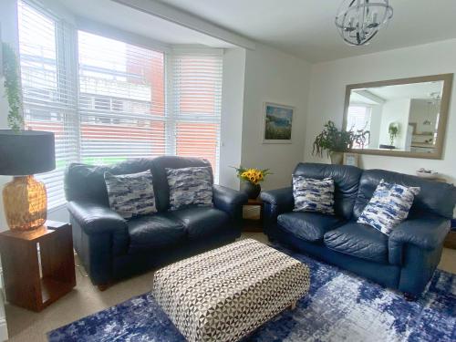 a living room with two leather chairs and a mirror at Percy House, 2 Bedroom, 4 Bed Flat Near Beach, Porthcawl Town Centre in Porthcawl