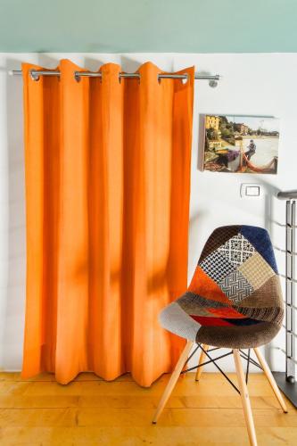 an orange curtain and a chair in a room at La Posta Di Cadimare - Chill in the Mezzanine Bedroom at a Former Post Office in Fezzano