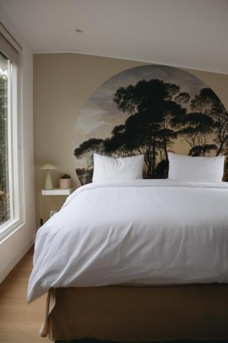 a bedroom with a large white bed with a painting on the wall at B&B La Balena in Zaandijk near Amsterdam in Zaandijk