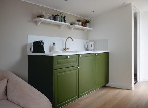 a kitchen with green cabinets and a sink at B&B La Balena in Zaandijk near Amsterdam in Zaandijk