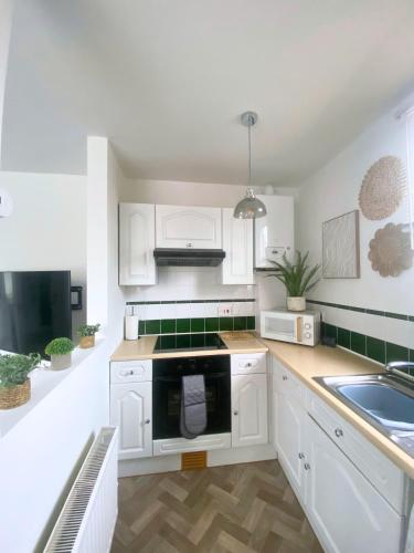 a kitchen with white cabinets and a stove top oven at Percy House, 2 Bedroom, 4 Bed Flat Near Beach, Porthcawl Town Centre in Porthcawl