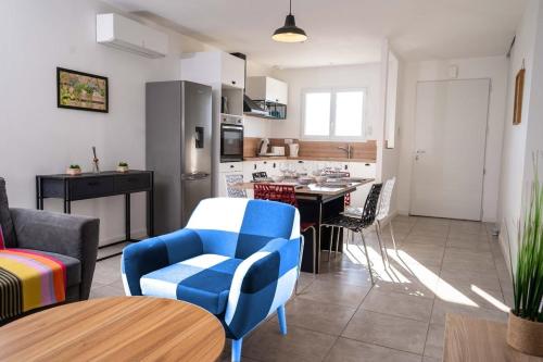une cuisine et un salon avec des chaises bleues et une table dans l'établissement La Maison Turquoise, à Giroussens