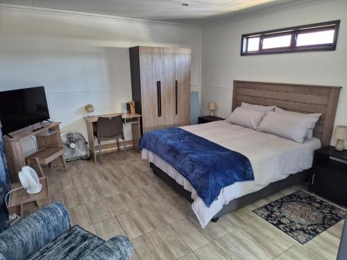 a bedroom with a bed and a tv and a couch at Wattlewood Cabins in Piet Retief