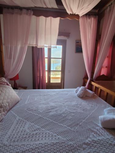 a bedroom with a large bed with pink curtains at Studio sunrise in Kámpos