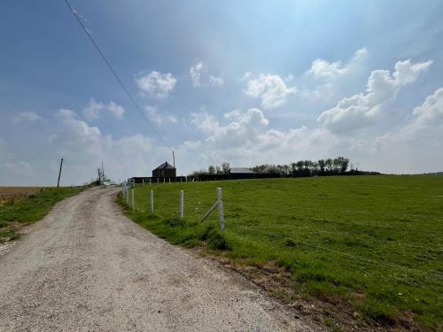a dirt road in a field with a fence at Gîte familial à la ferme des Hellandes in Angerville-lʼOrcher