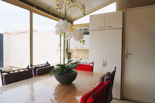 une salle à manger avec une table et un vase fleuri dans l'établissement Le Lagon Clim Parking 4Pers, à Port-la-Nouvelle