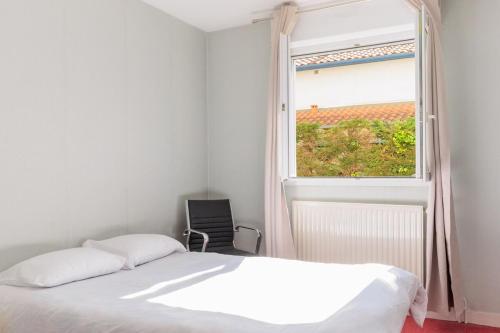 une chambre avec un lit et une fenêtre avec une chaise dans l'établissement Comfortable Apartment Close to Biarritz Beach and City Center, à Biarritz