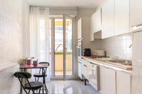 une cuisine avec des armoires blanches et une table et des chaises dans l'établissement Comfortable Apartment Close to Biarritz Beach and City Center, à Biarritz