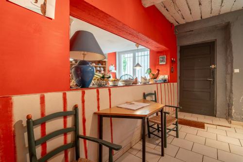 une cuisine avec des murs rouges et une table et des chaises dans l'établissement Massenet, à Lapalme