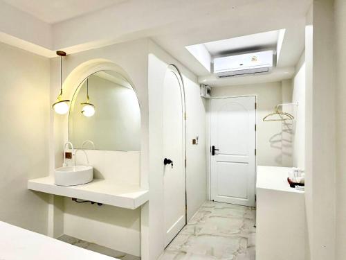 a white bathroom with a sink and a mirror at Evelia Kohsamed in Ao Phutsa