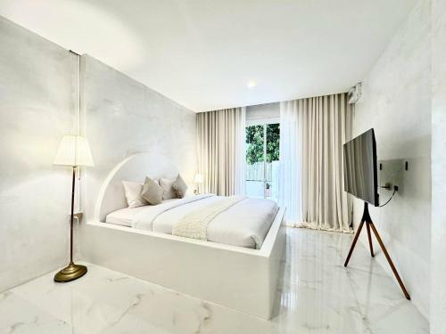 a white bedroom with a bed and a television at Evelia Kohsamed in Ao Phutsa