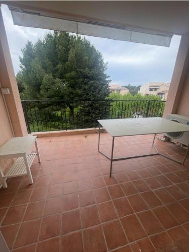 d'un balcon avec un banc et une vue sur un arbre. dans l'établissement Confort, à la mer, tout à pied !, à Six-Fours-les-Plages