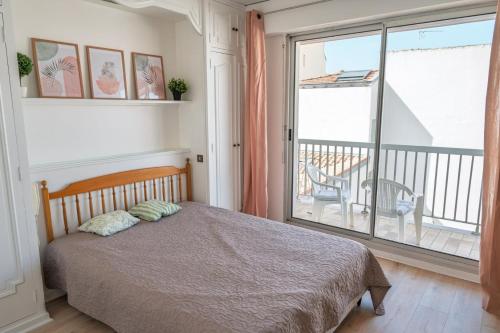 une chambre avec un lit et une grande fenêtre dans l'établissement Appartement Les Coraux, centre & plage, à Arcachon