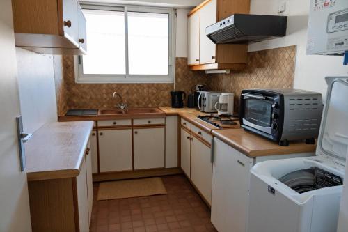 une petite cuisine avec un évier et un micro-ondes dans l'établissement Appartement Les Coraux, centre & plage, à Arcachon