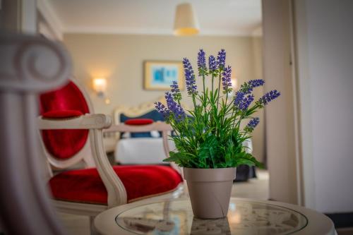 a vase with purple flowers on a glass table at Alexain Hotel Restaurant & Wellness - Colmar Ouest in Trois-Épis