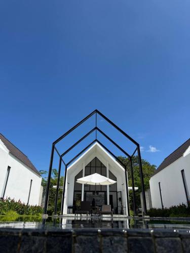 a building with a table and an umbrella at Ezu Isle Langkawi Pool Villa in Pantai Cenang