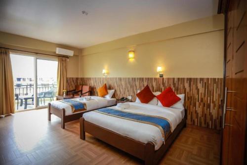 a hotel room with two beds and a balcony at Pokhara Crown Plaza in Pokhara