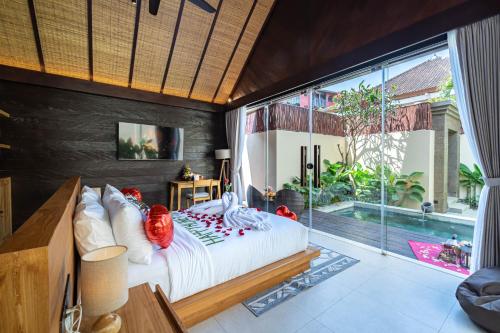 a bedroom with a bed and a large window at Villa Bolon in Kuta