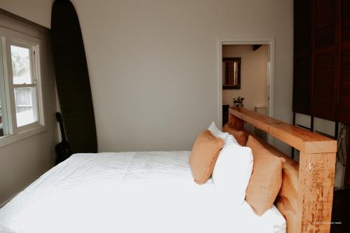 a bedroom with a white bed with a wooden headboard at Evans Head Beach House - Entertainer in Evans Head