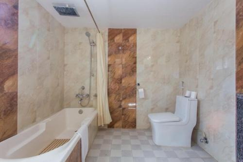 a bathroom with a tub and a toilet and a shower at Pokhara Crown Plaza in Pokhara
