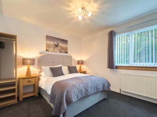 a bedroom with a bed and two lamps and a window at Kilmore Farmhouse in Drumnadrochit