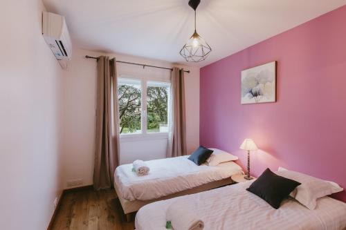 - 2 lits dans une chambre avec un mur rose dans l'établissement Appartement T3, spacieux, climatisé, cosy, à Bassens